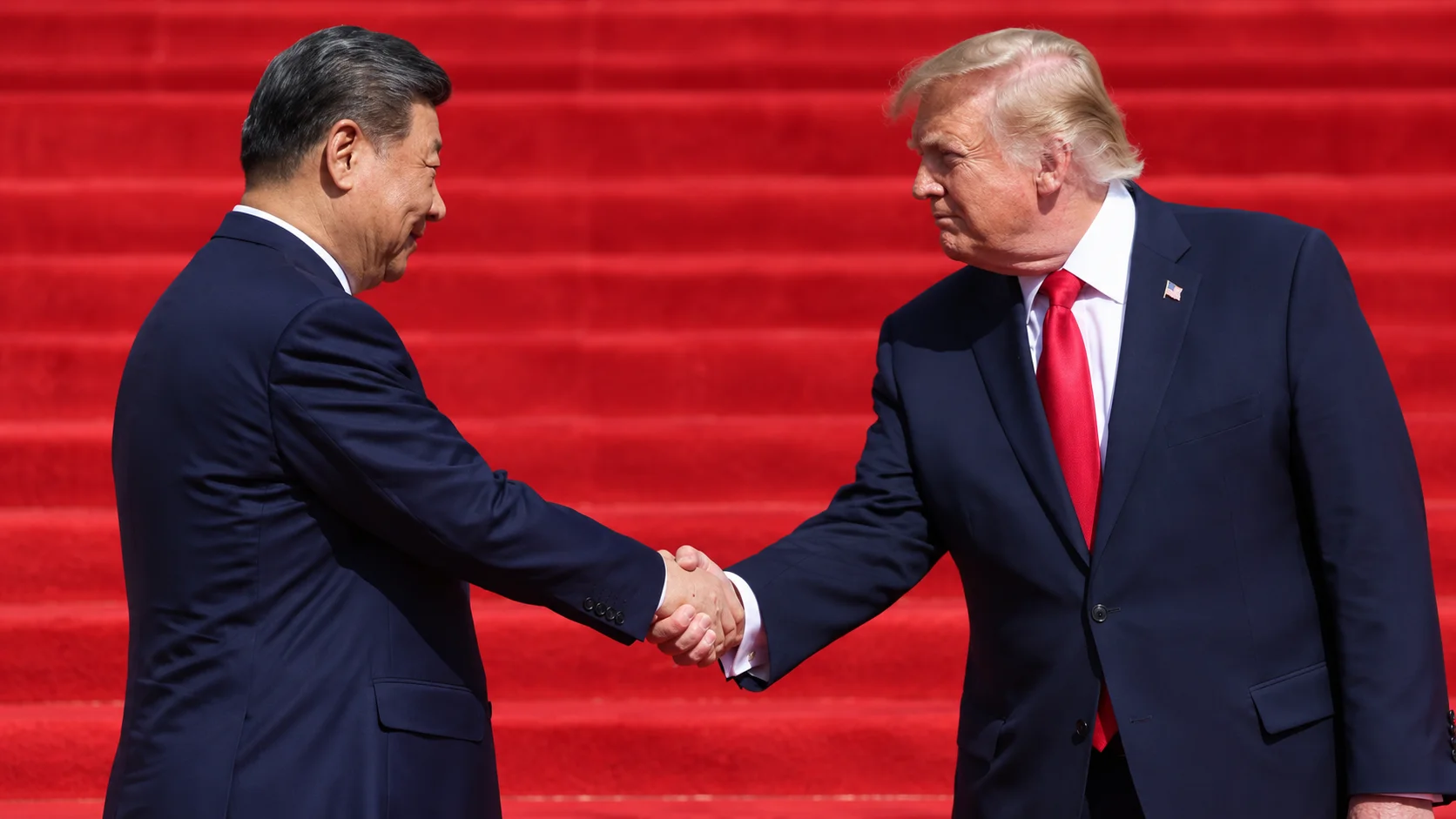Xi Jinping and Donald Trump shaking hands in front of a red staircase.