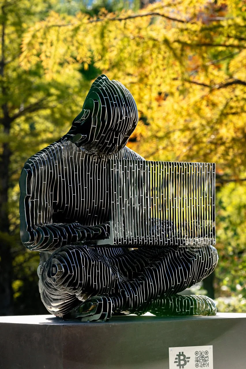 Vista lateral da estátua de Satoshi Nakamoto em Viena revela as 61 camadas de aço inoxidável que formam a figura do criador do Bitcoin. Foto: Max Peternell / Bitcoin Austria.